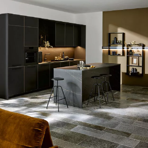 Zeitlose Nolte Küche in Schwarz mit Kücheninsel aus Stein, integrierten Geräten und Sitzplätzen, edle Materialien und warmes Licht für modernes Kochen